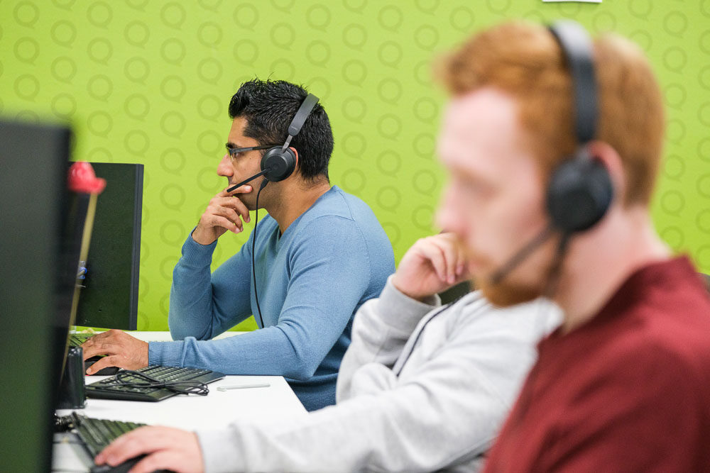 Microsoft partner experts talking on phone headsets while working at desktop computers
