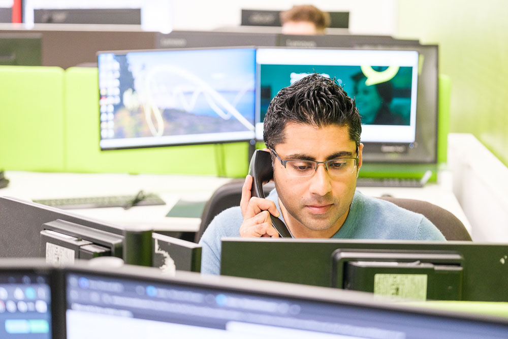 Cisco partner expert working at a desktop computer while talking on a mobile phone