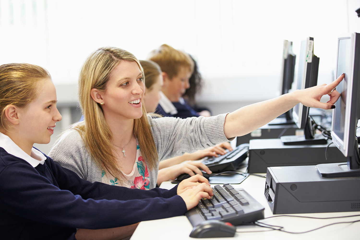 Education frameworks supporting and keeping students safe while learning at a desktop computer with a teacher.