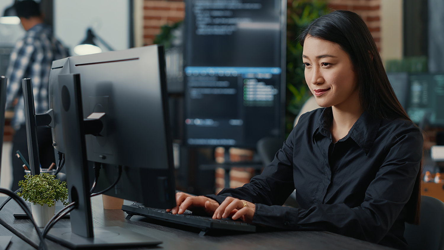 Microsoft licensing and security supporting female worker sitting at a desktop computer in an office