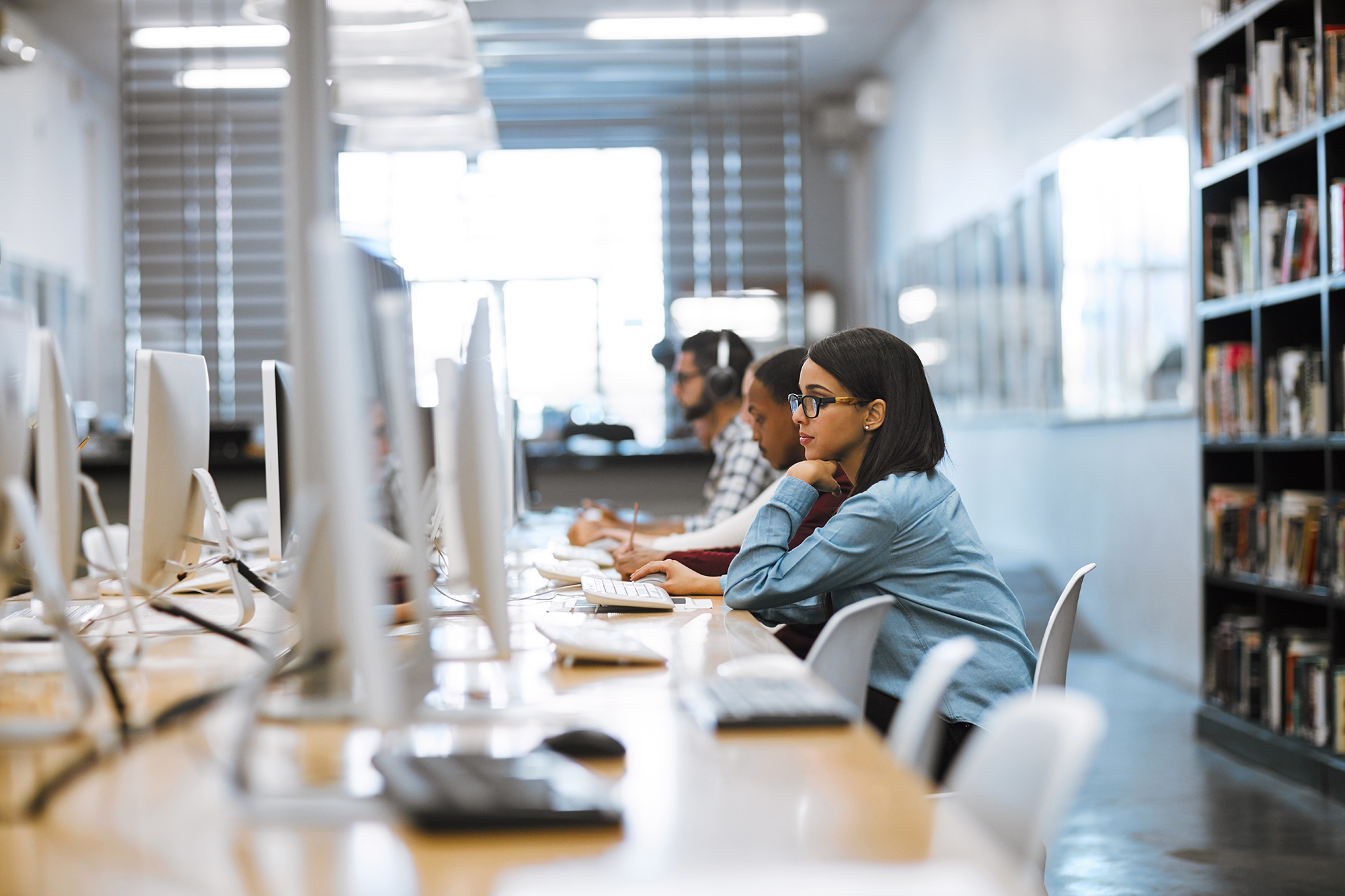 Responsive helpdesk for education supporting a student working at a desktop computer in a library.